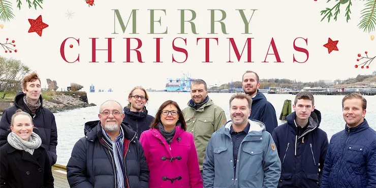 Julkort med texten »Merry Christmas« i granris och kulor, och ett foto av SeaTwirls medarbetare i vinterkläder vid vattnet