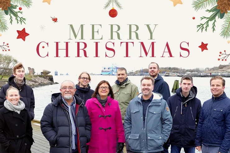 Julkort med texten »Merry Christmas« i granris och kulor, och ett foto av SeaTwirls medarbetare i vinterkläder vid vattnet