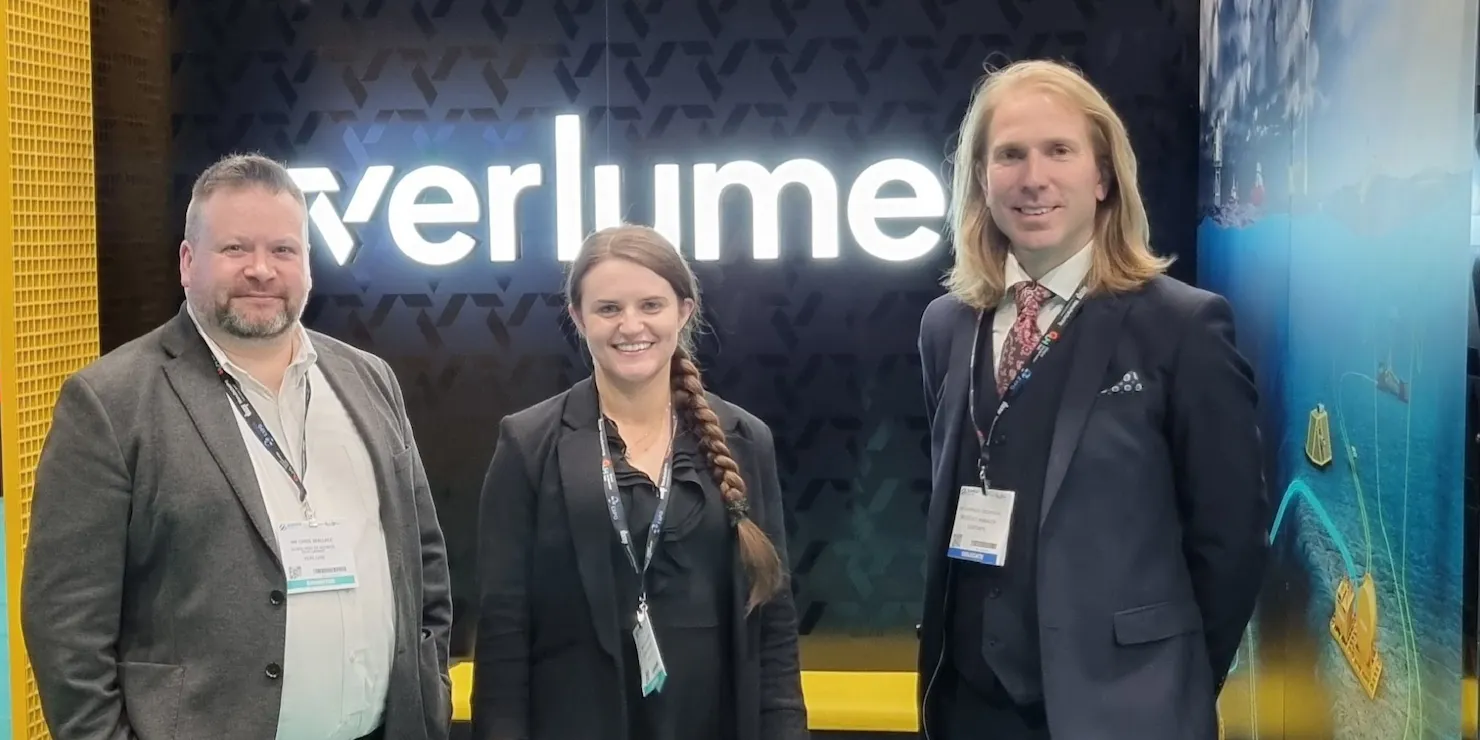 Tre personer framför Verlumes upplysta mässmonter på Subsea Expo