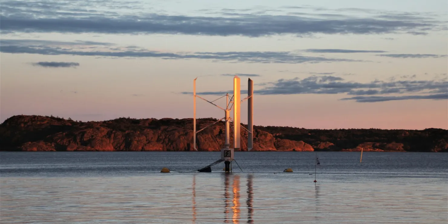 Prototypen SeaTwirl S1 i solnedgång med ett klippigt skär bakom och orange ljus över vattnet