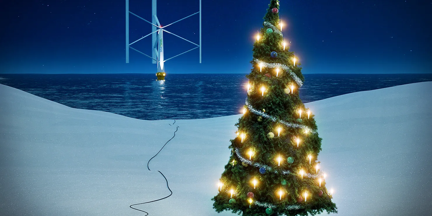 Julillustration: en tänd julgran i snön vid vattenbrynet, med en kabel som löper ut i havet till ett flytande vertikalaxlat vindkraftverk